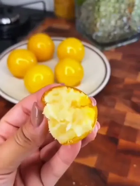 Mão segurando uma bala caramelizada aberta, com o recheio cremoso à mostra